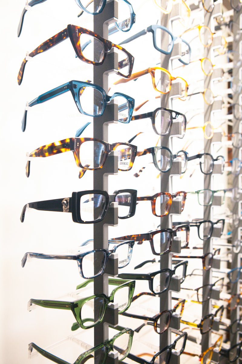 Diverse selection of eyeglass frames in various styles and colours on dark display stand